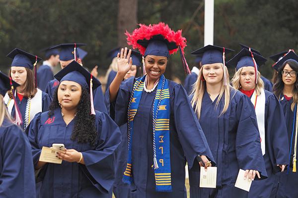 Students in cap and gowns walking to graduation.